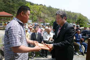 ▲ 강병년 이장이 마을일에 앞장선 이동호씨에게 감사패를 주고 있다.