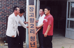 ▲ 유명천 회장을 비롯한 내빈들이 청년회 발족을 축하하며 마을회관에 현판을 걸고 있다.