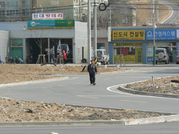 ▲ 완공을 앞둔 읍내토지구획정리지구 내에서 한 주민이 차로 위를 걷고 있다. 단지내에 차 다닐 차로와 빗물이 흐를 측구는 있어도 사람 다닐 인도는 없다.