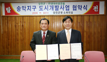 ▲ 민종기군수와 강현식(주)엠아이엠건설 대표가 행정서에 서명한 후 기념촬영을 하고 있다.
