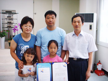 ▲ 책읽는 가족으로 선정된 우인상씨 가족과 한경석(오른쪽) 도서관장의 모습.