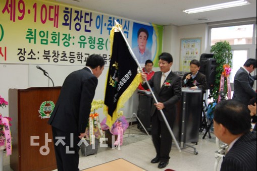 최문호 이임회장이 유형용 신임회장에게 총동문회기를 전달하고 있다.