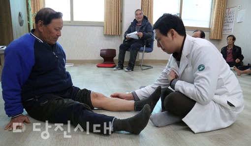 ▲ 서용인 한의사가 노인의 아픈 다리에 침을 놔주고 있다.