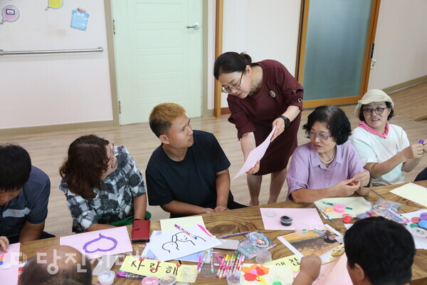 김옥자 순성면 분회장(서 있는 사람)이 한빛공동체 이용자들에게 클레이 활동들을 진행하고 있다.