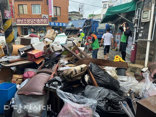 지난해 수해 피해로 버려진 집기와 세간살이를 자원봉사자들이 도와 폐기하고 있다.